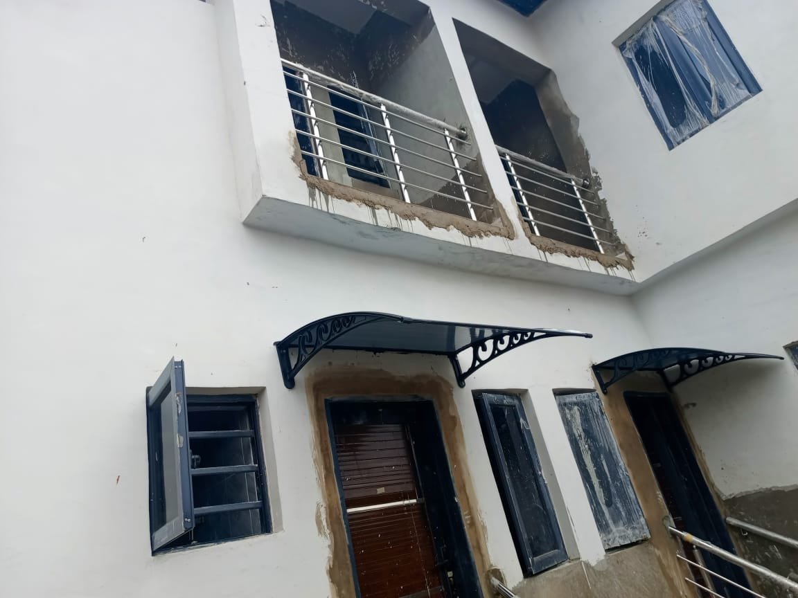 White facade of Alagbole block showing balconies upstairs and ground-floor entrances