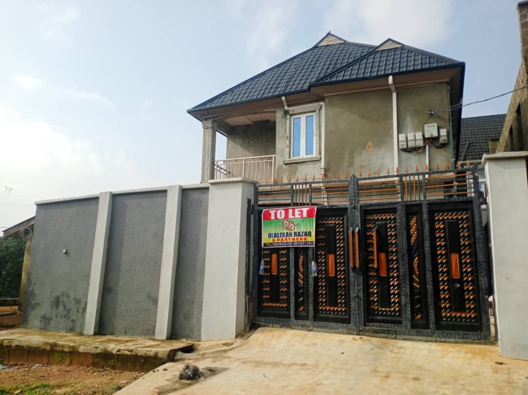 Side view of the two-storey Alagbole residential block and black ornamental gate
